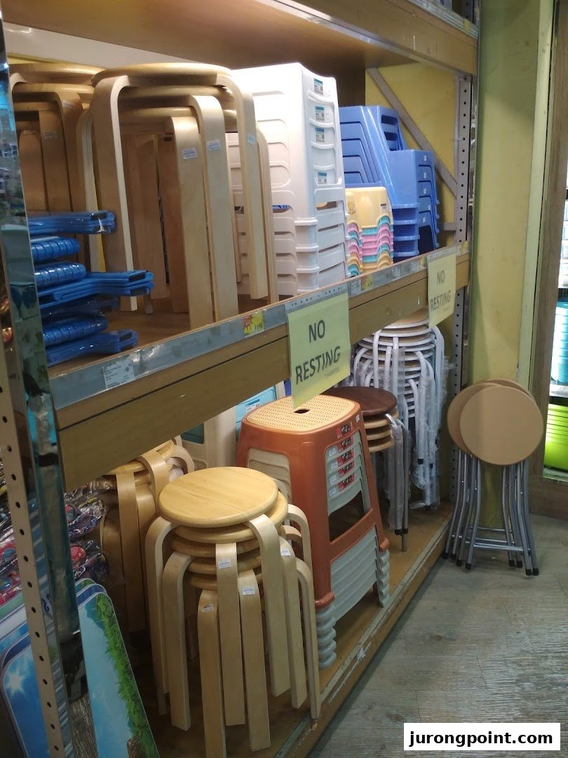 Various types of stools and chairs, including wooden and plastic designs, stacked on shelves in a retail store.