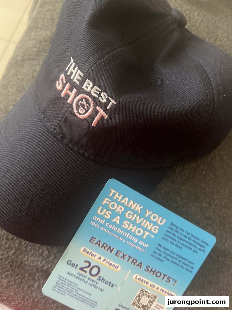 A dark blue cap with 'THE BEST SHOT' embroidery and a Japan IPL Express promotional card.
