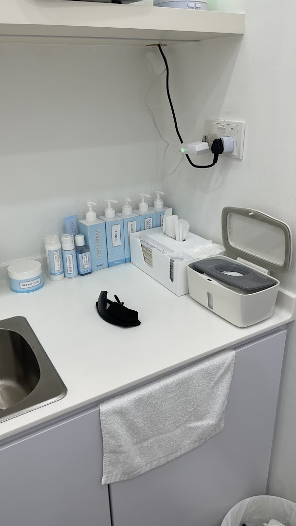 A clean counter with skincare products, a sink, and supplies in a treatment room.