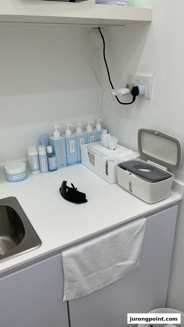 A clean counter with skincare products, a sink, and supplies in a treatment room.