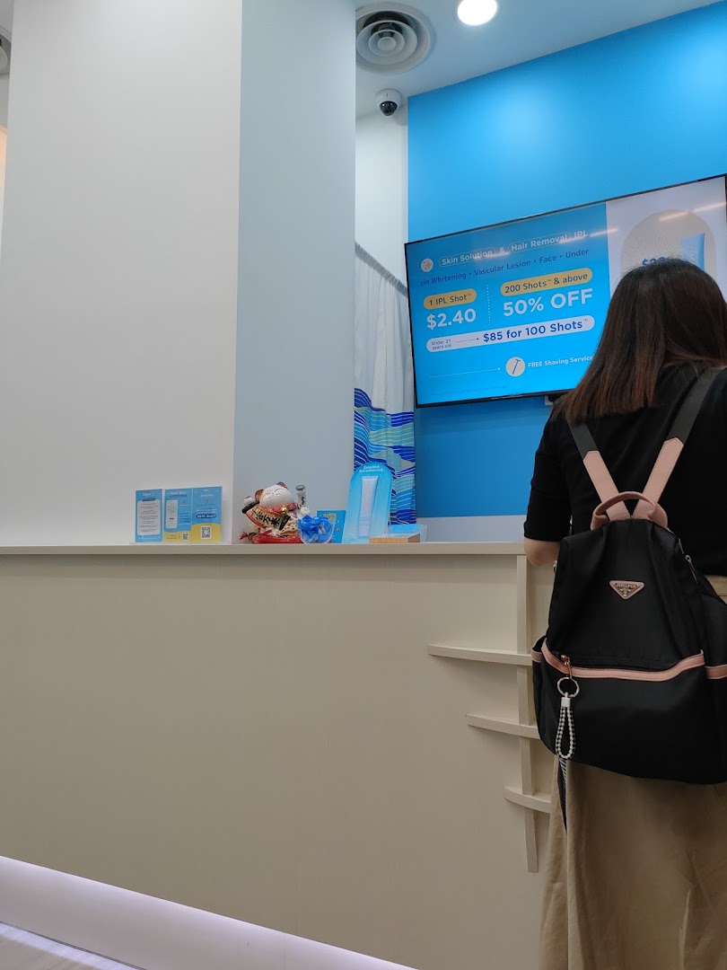 A customer stands at the counter of Japan IPL Express, facing a digital display advertising IPL services.
