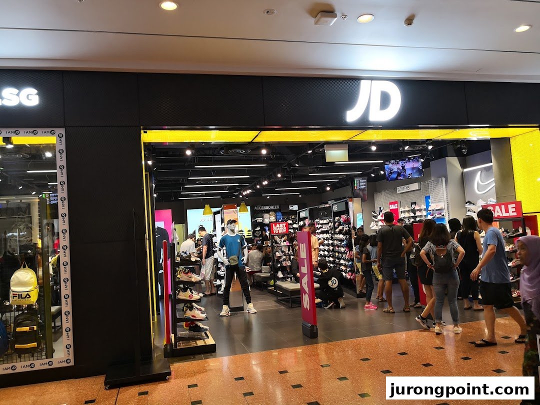 The bustling entrance of JD Sports, showcasing a wide range of sportswear and sneakers with customers browsing.