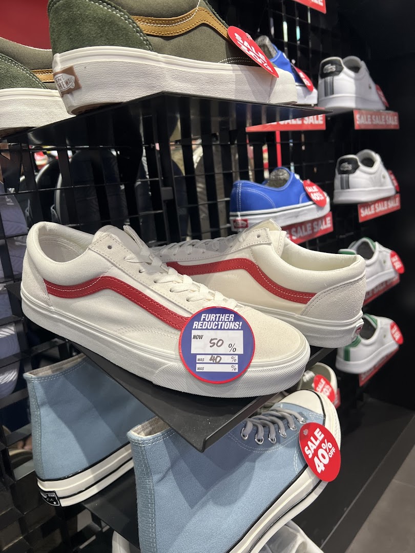 A vibrant display of various sneakers, including Vans and Converse, with prominent sale tags indicating discounts.