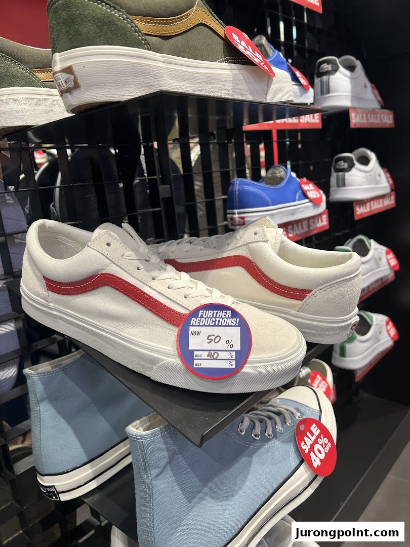 A vibrant display of various sneakers, including Vans and Converse, with prominent sale tags indicating discounts.