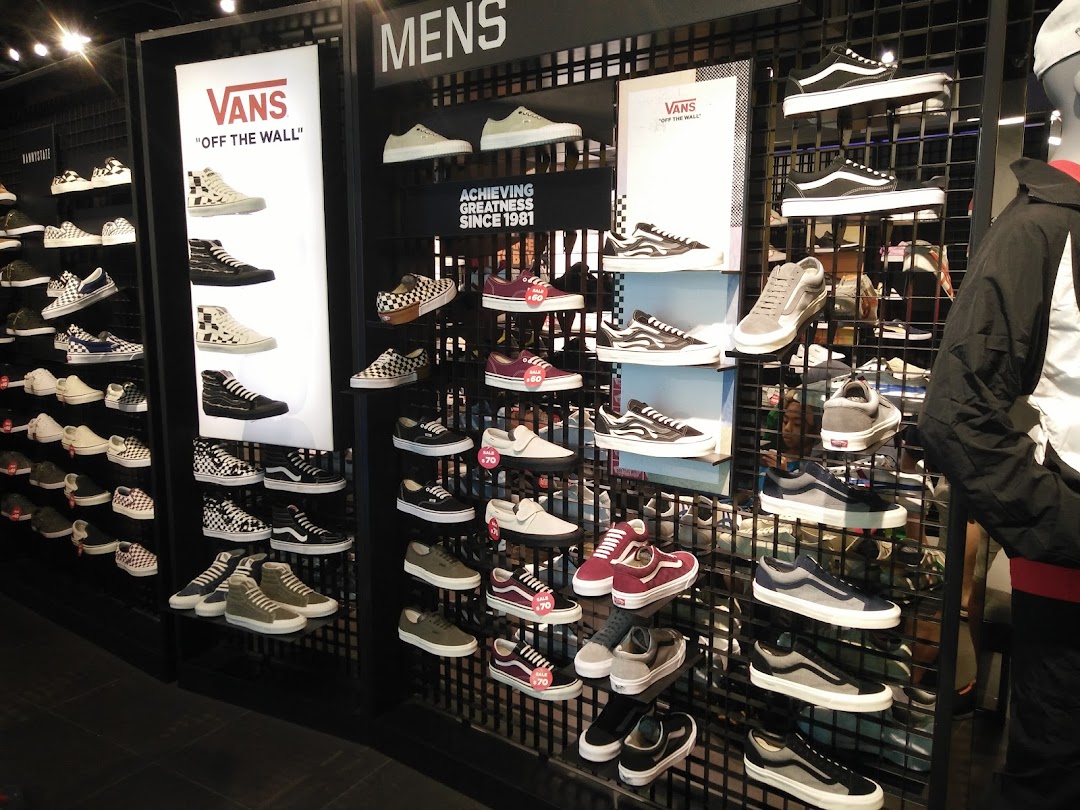 A vibrant display of Vans sneakers and other athletic footwear on shelves in a retail store.