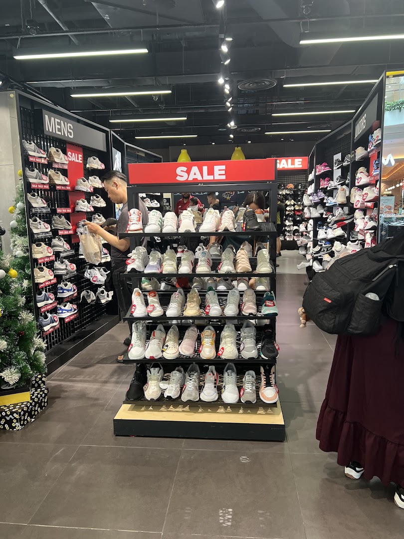 An interior view of JD Sports showcasing a wide selection of sneakers on display, with customers browsing.
