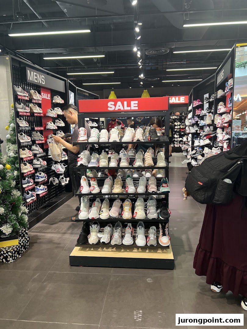 An interior view of JD Sports showcasing a wide selection of sneakers on display, with customers browsing.