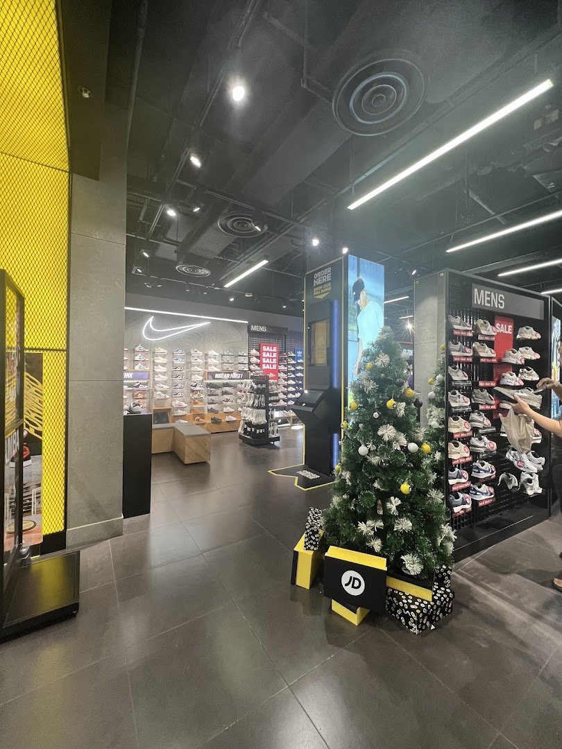 Interior view of JD Sports, showcasing footwear displays, a 'MENS' section, and festive Christmas decorations.