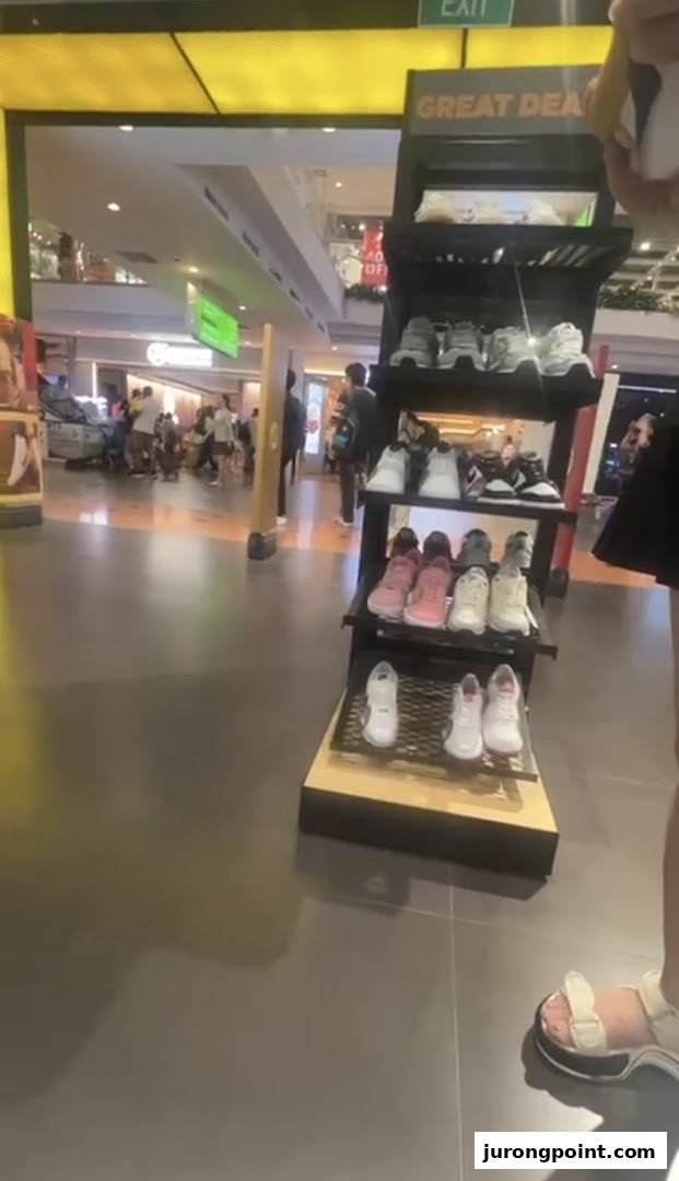 An in-store display showcasing a variety of athletic footwear, with shoppers in the background.