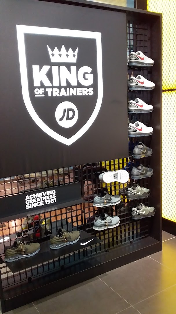 A JD Sports display featuring various trainers and the 'King of Trainers' slogan.