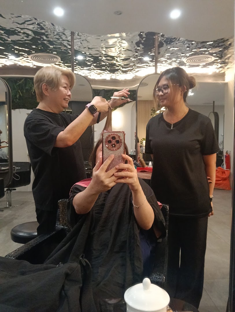 A customer receives a haircut from a stylist at Jean Yip Hairdressing, with another staff member present.