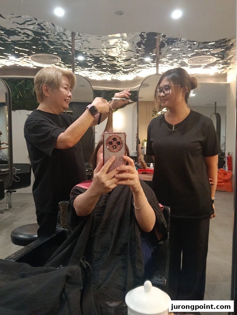 A customer receives a haircut from a stylist at Jean Yip Hairdressing, with another staff member present.