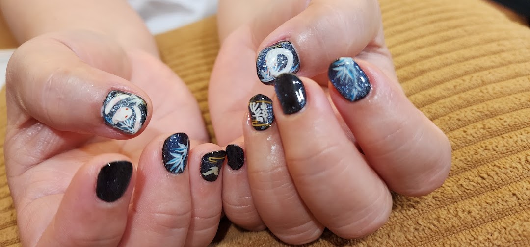 Close-up of hands displaying intricate dark blue and glitter nail art with white, Asian-inspired designs.