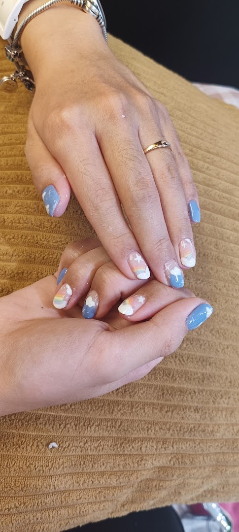 Close-up of hands showcasing creative nail art with clouds, rainbows, and stars.