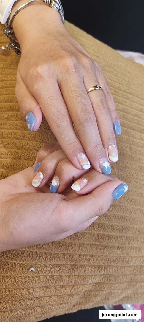 Close-up of hands showcasing creative nail art with clouds, rainbows, and stars.