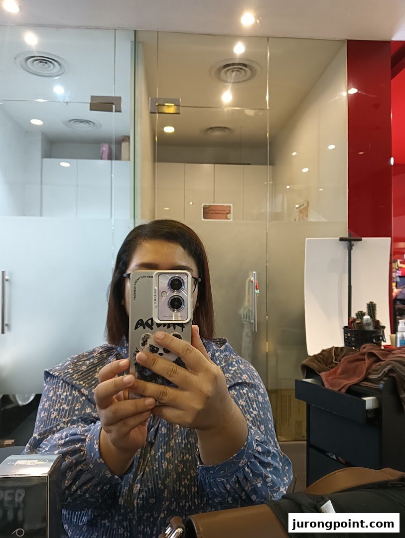 A person taking a selfie inside Jean Yip Hairdressing, showing the salon's interior with mirrors and equipment.