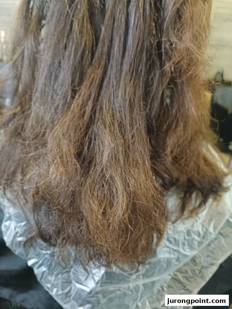 Close-up of hair undergoing a treatment, likely coloring or perming, at a salon.