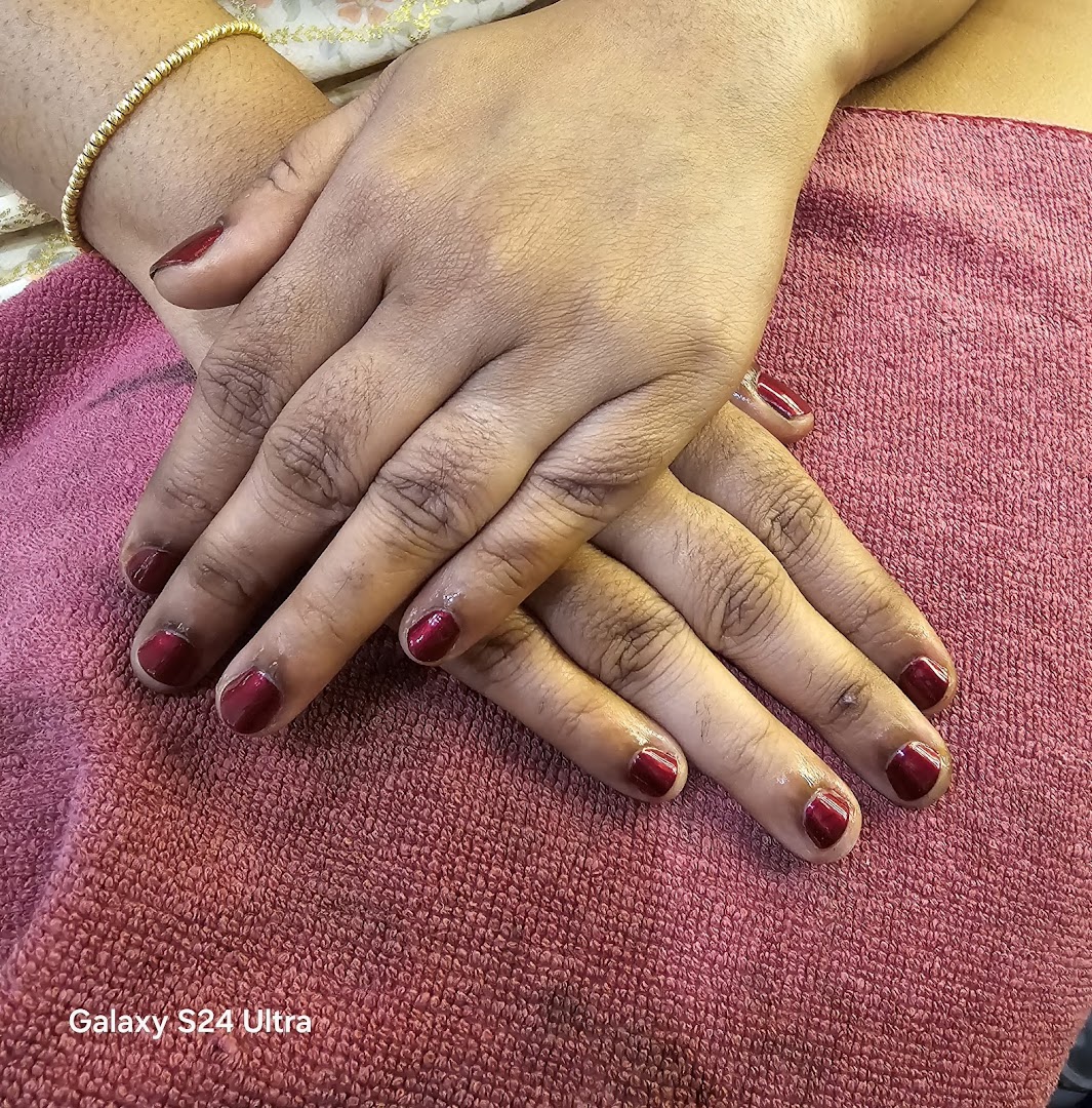 Close-up of hands with freshly painted red nails resting on a pink towel.