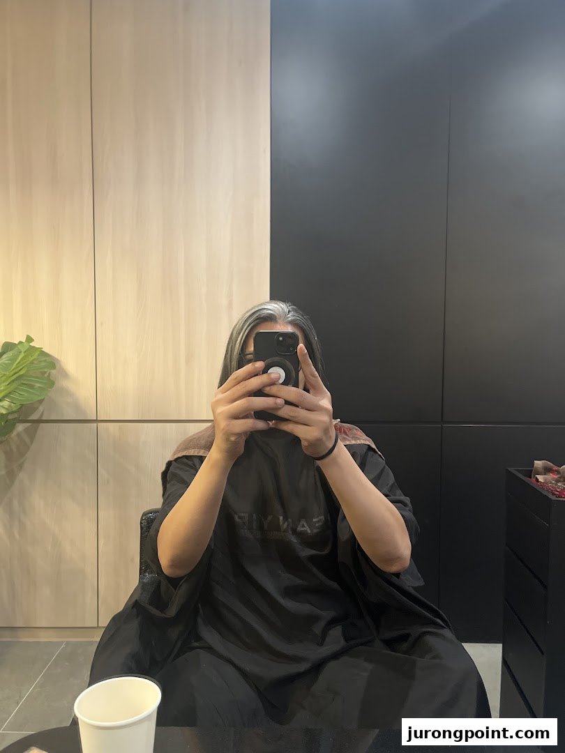 A client takes a mirror selfie inside Jean Yip Hairdressing, showcasing the salon's modern interior.