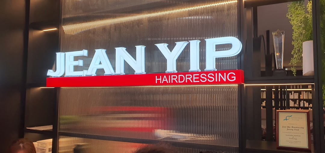 An illuminated 'Jean Yip Hairdressing' sign with modern interior decor and a visible award.