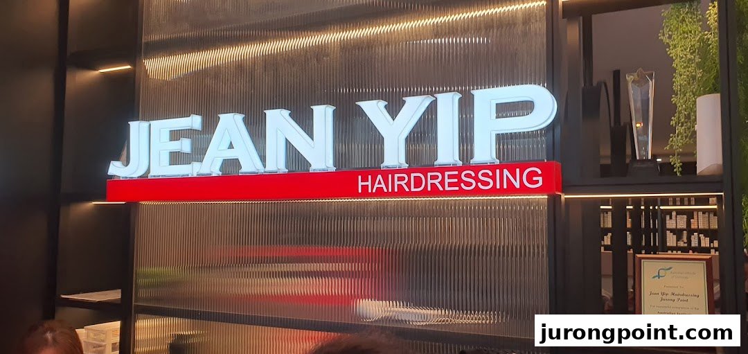 An illuminated 'Jean Yip Hairdressing' sign with modern interior decor and a visible award.