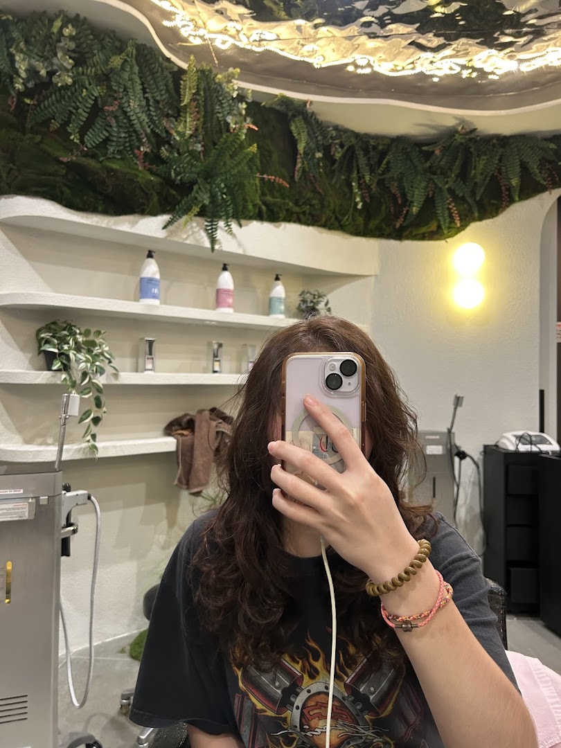 A customer takes a selfie inside Jean Yip Hairdressing, showcasing the salon's modern and green interior.