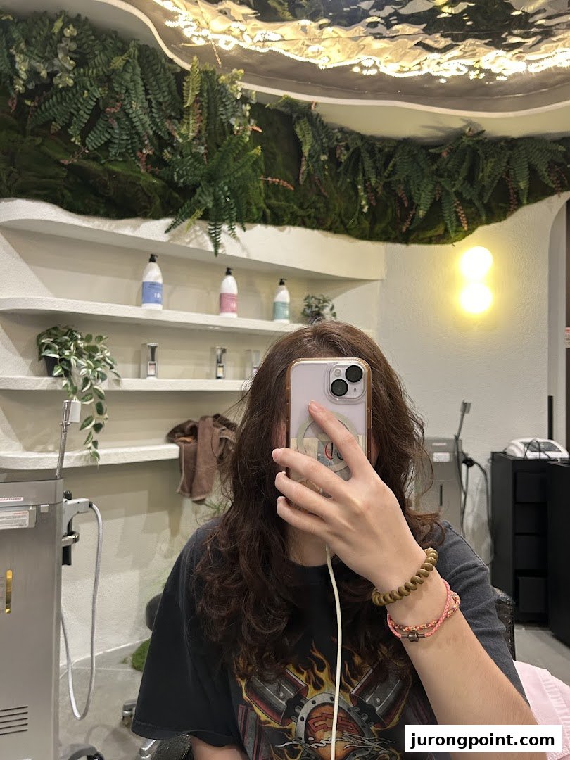A customer takes a selfie inside Jean Yip Hairdressing, showcasing the salon's modern and green interior.