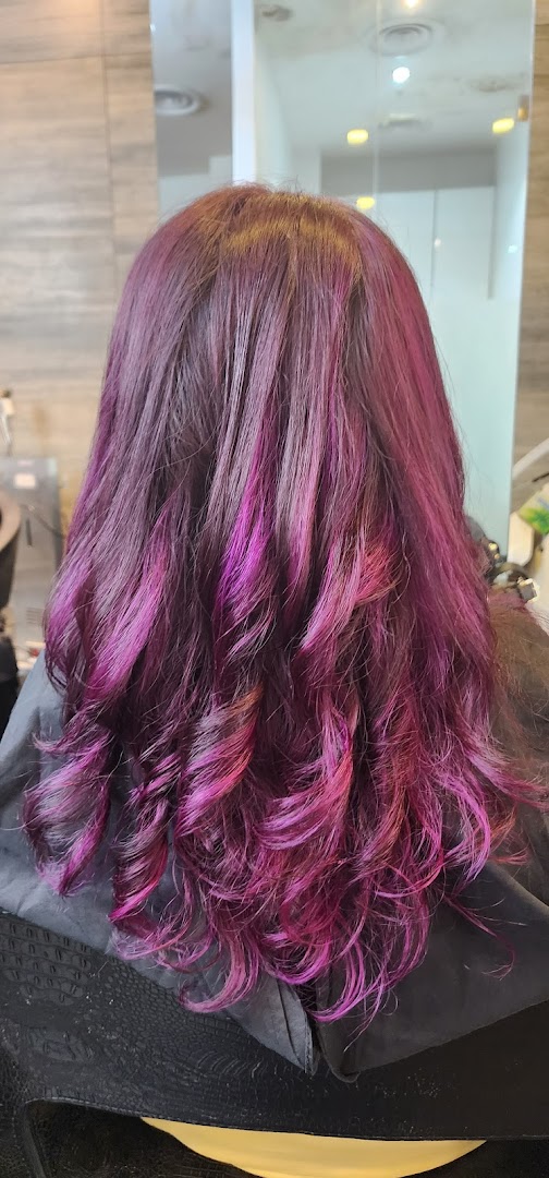 Vibrant purple and pink hair with soft curls, showcasing a salon's styling expertise.