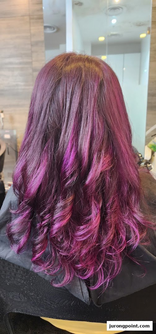 Vibrant purple and pink hair with soft curls, showcasing a salon's styling expertise.