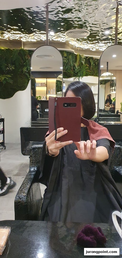 A customer takes a selfie in a modern hair salon, showcasing the stylish interior and services.