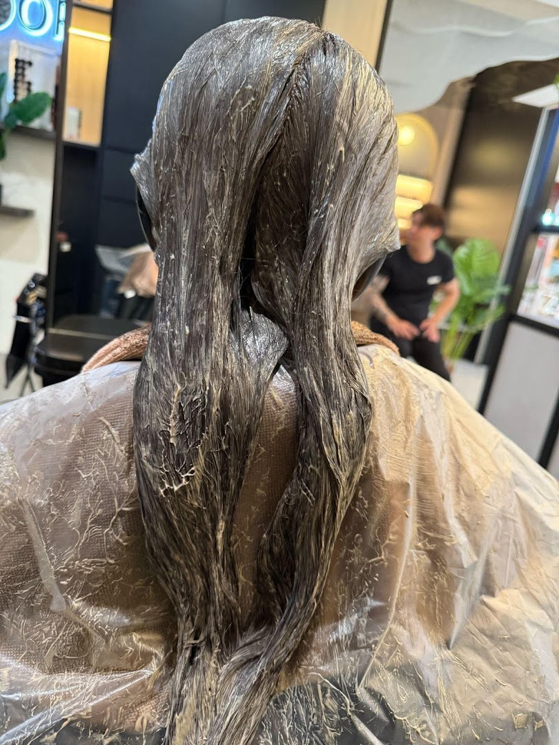 A client's hair undergoing treatment, likely coloring or perming, at Jean Yip Hairdressing salon.