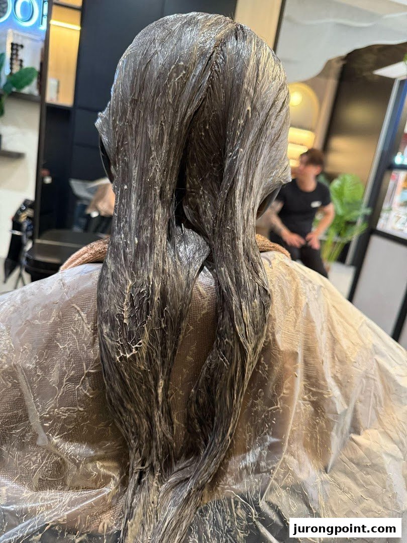 A client's hair undergoing treatment, likely coloring or perming, at Jean Yip Hairdressing salon.