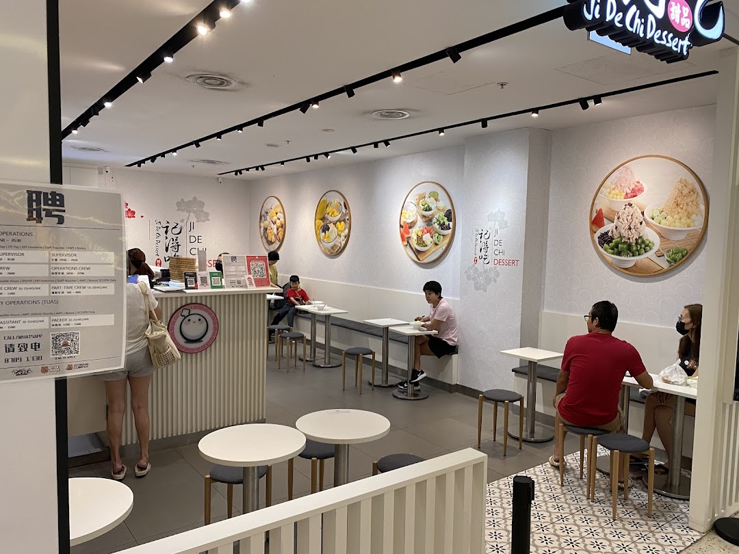 Interior view of Ji De Chi Dessert, featuring customers, seating, and vibrant dessert wall art.