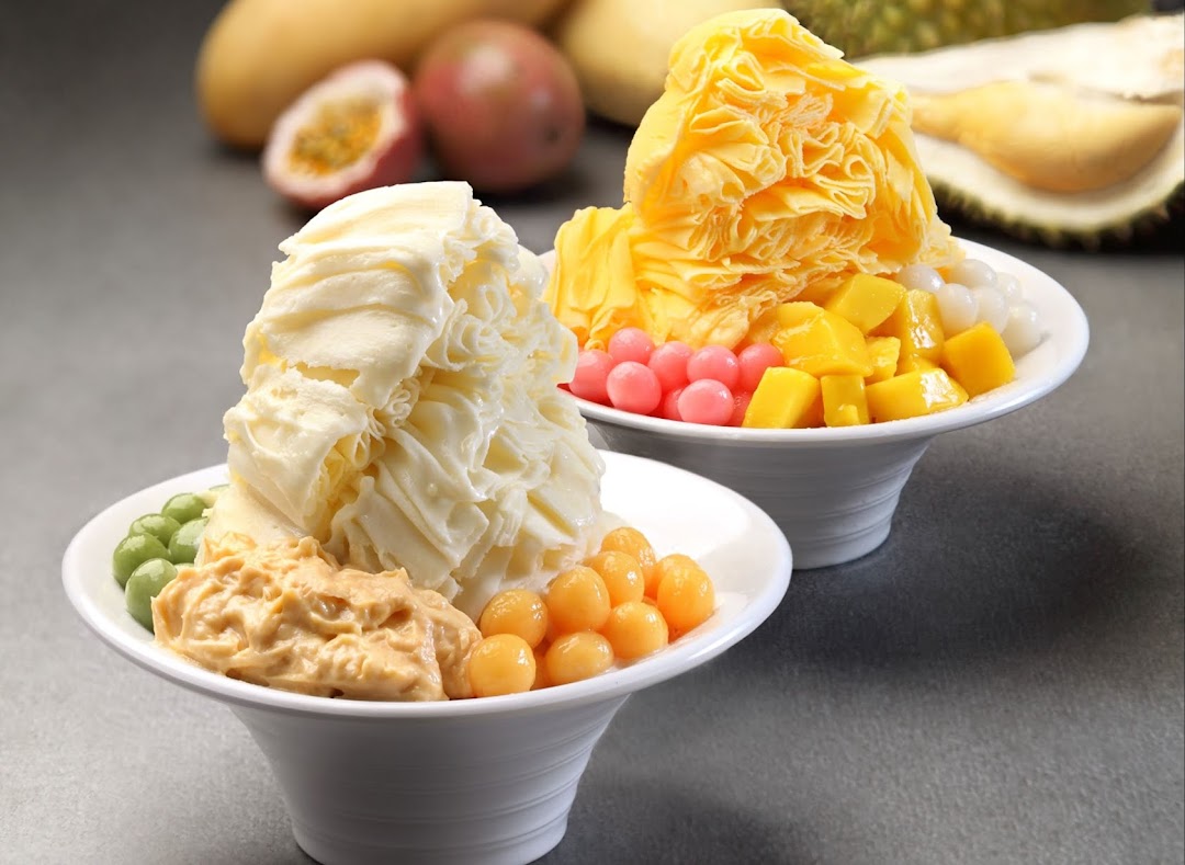 Two bowls of colorful shaved ice desserts with various fruit toppings and pearls.