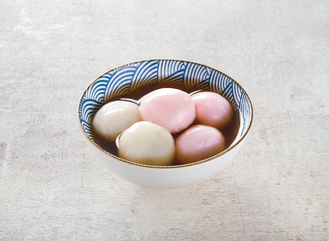 A bowl of colorful tangyuan (glutinous rice balls) in a sweet soup, showcasing a dessert item.