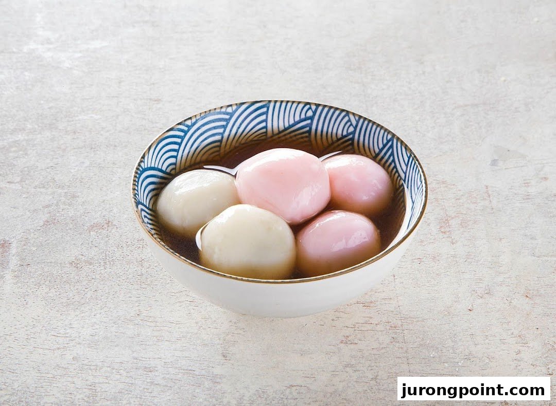 A bowl of colorful tangyuan (glutinous rice balls) in a sweet soup, showcasing a dessert item.