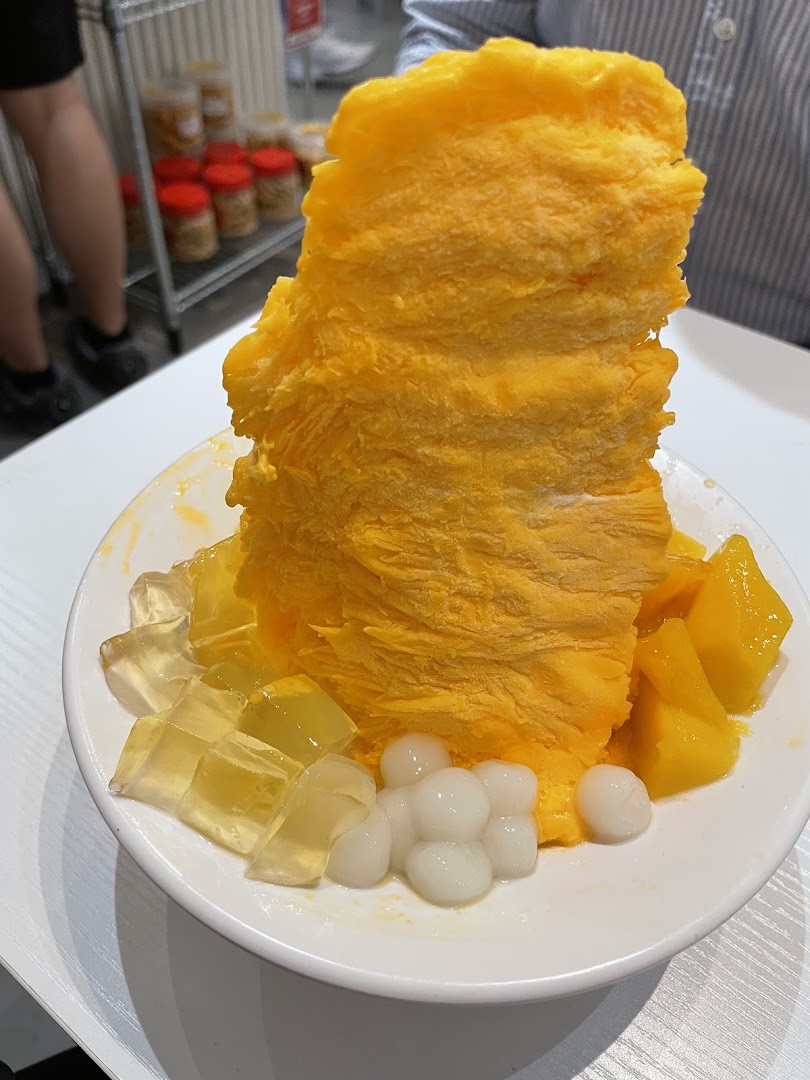 A vibrant mango shaved ice dessert with fresh mango cubes, jelly, and chewy pearls.