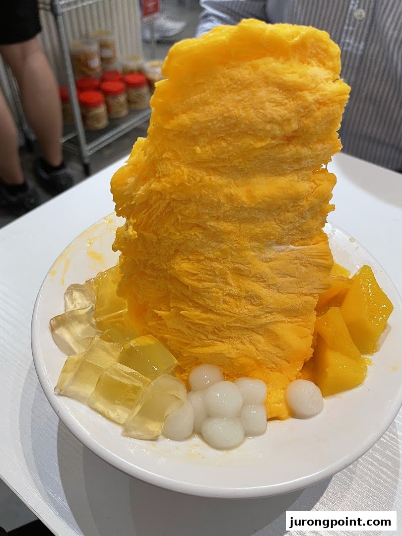 A vibrant mango shaved ice dessert with fresh mango cubes, jelly, and chewy pearls.