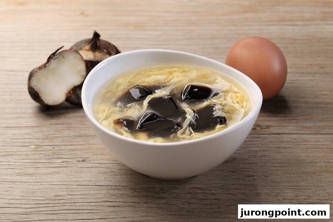 A bowl of traditional Chinese dessert soup with egg and herbal jelly, alongside fresh ingredients.
