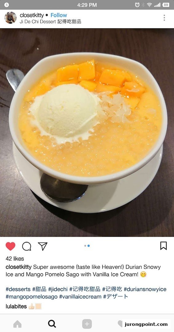 A vibrant bowl of mango pomelo sago dessert topped with vanilla ice cream and fresh mango chunks.