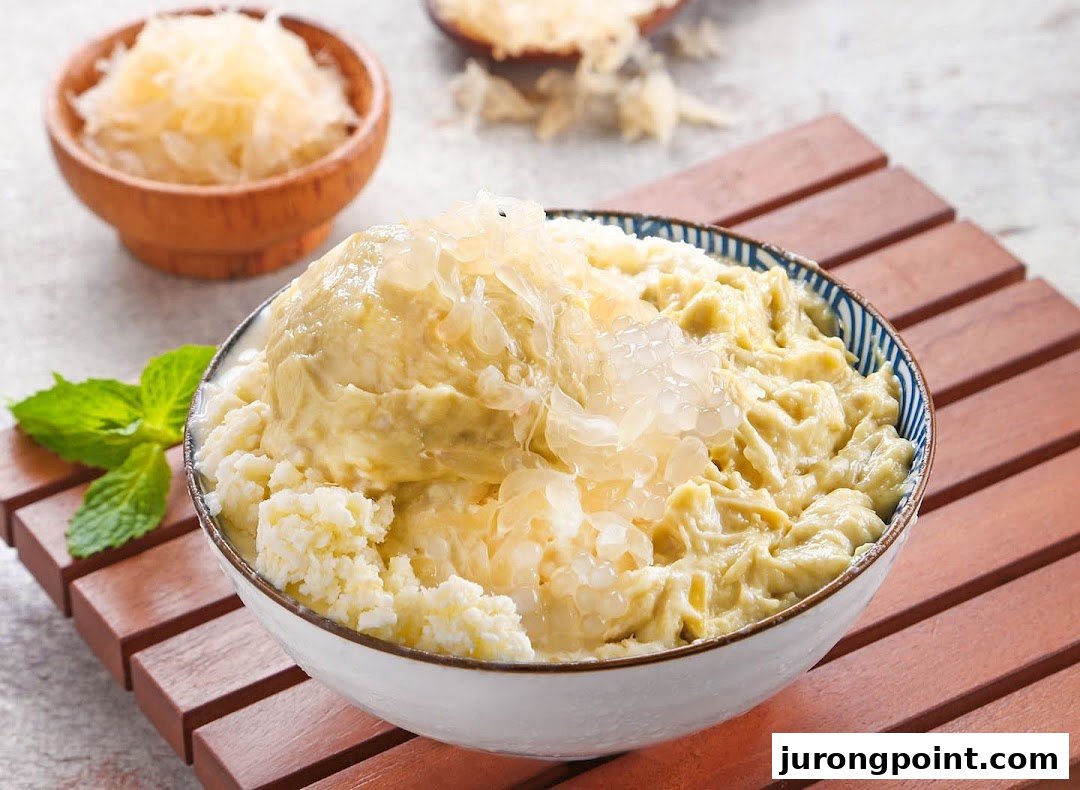 A bowl of creamy durian dessert topped with fresh pomelo, served on a wooden tray.