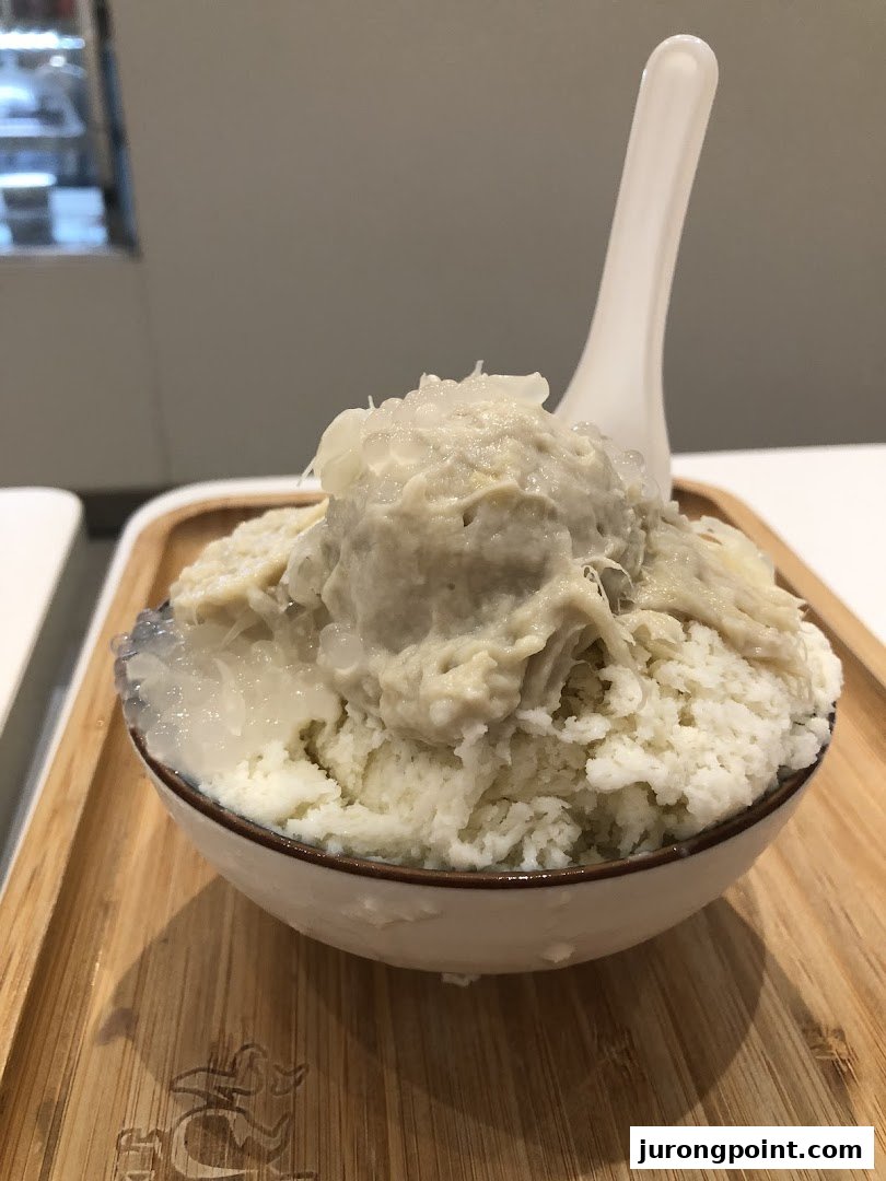 A close-up of a refreshing durian-flavored shaved ice dessert with toppings in a bowl.