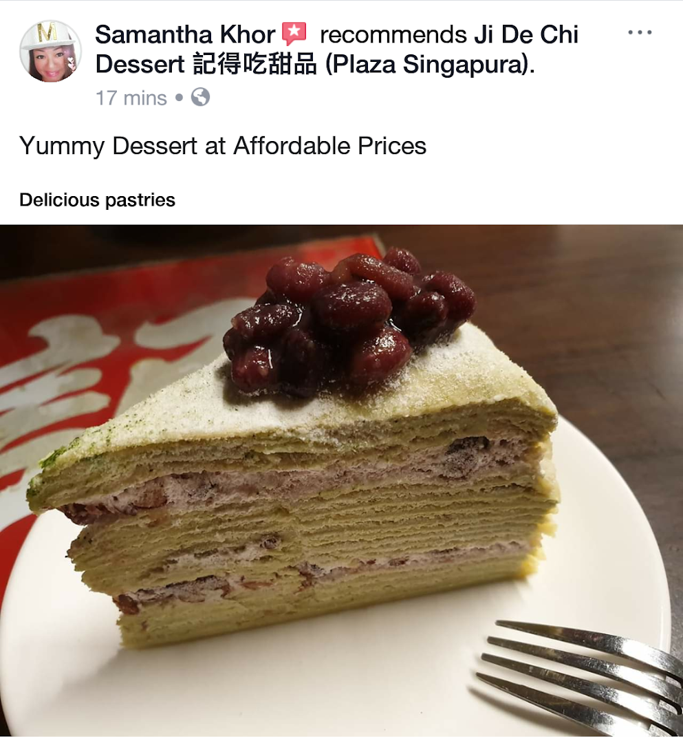 A delicious slice of matcha crepe cake topped with sweet red beans on a white plate.