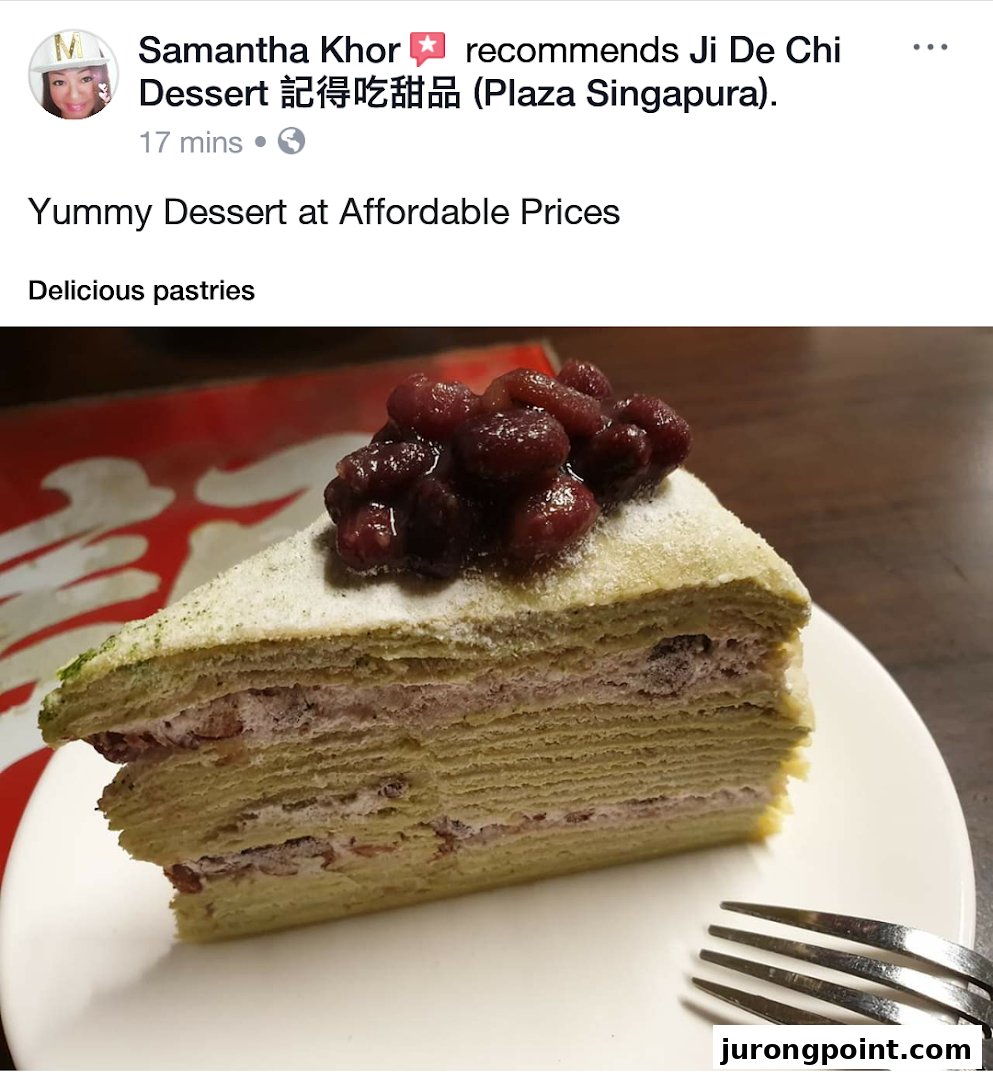 A delicious slice of matcha crepe cake topped with sweet red beans on a white plate.