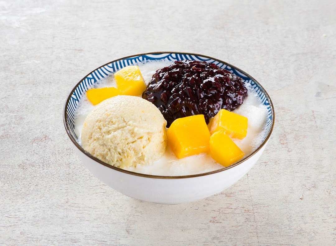 A delicious bowl of dessert with ice cream, mango, and black glutinous rice in a milky base.