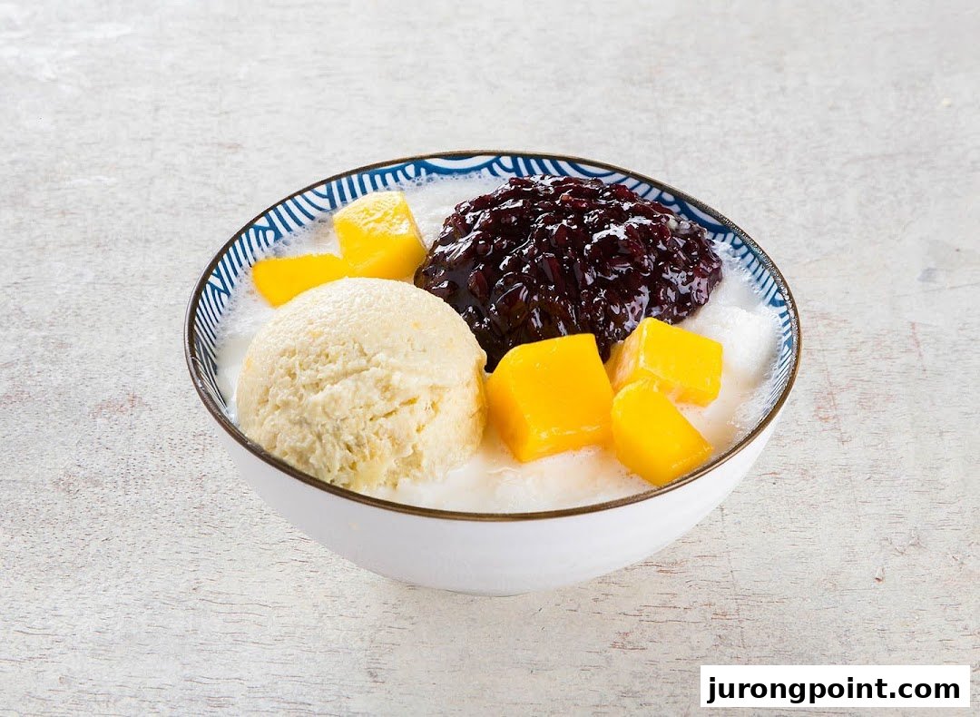 A delicious bowl of dessert with ice cream, mango, and black glutinous rice in a milky base.