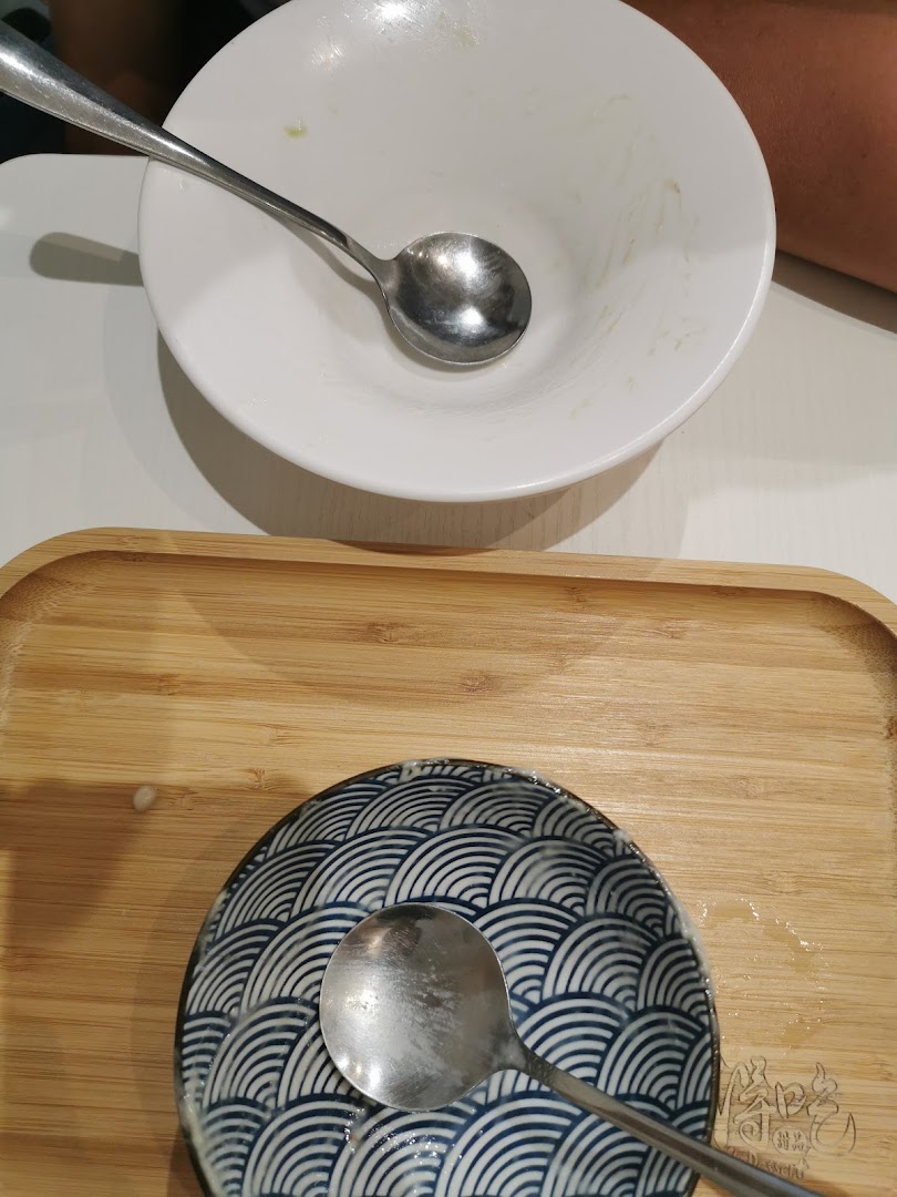An empty dessert bowl and a small patterned plate with spoons on a wooden tray.