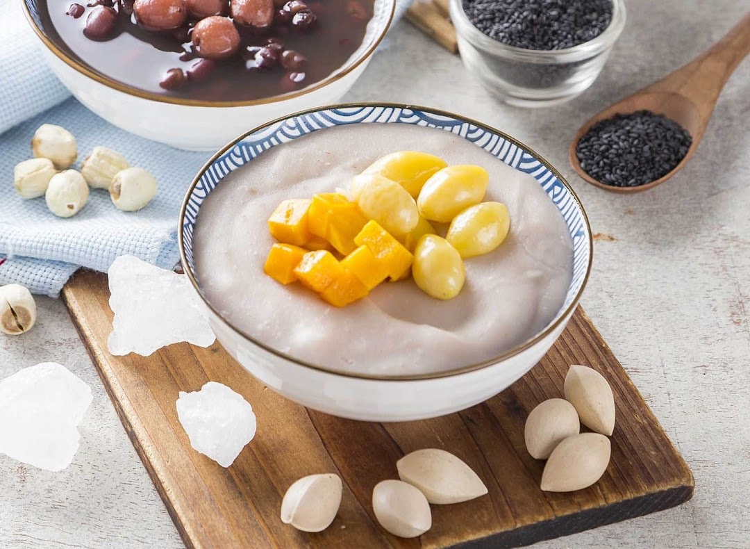 Two bowls of traditional Asian desserts, featuring taro paste with ginkgo and mango, and red bean soup.