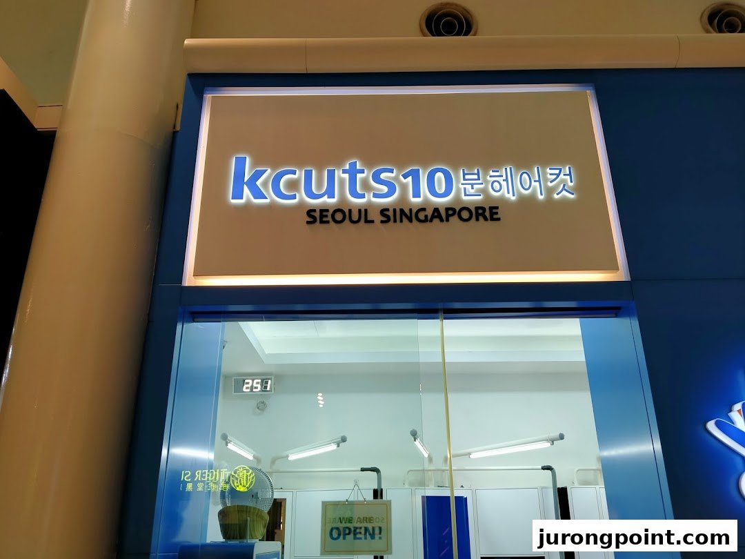 The illuminated storefront of kcuts10, a hair salon, featuring its name and 'SEOUL SINGAPORE'.