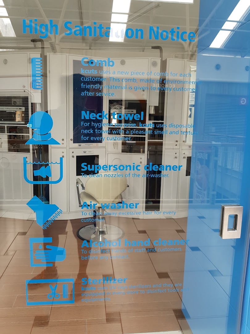 An interior view of kcuts hair salon through a glass door displaying a high sanitation notice.